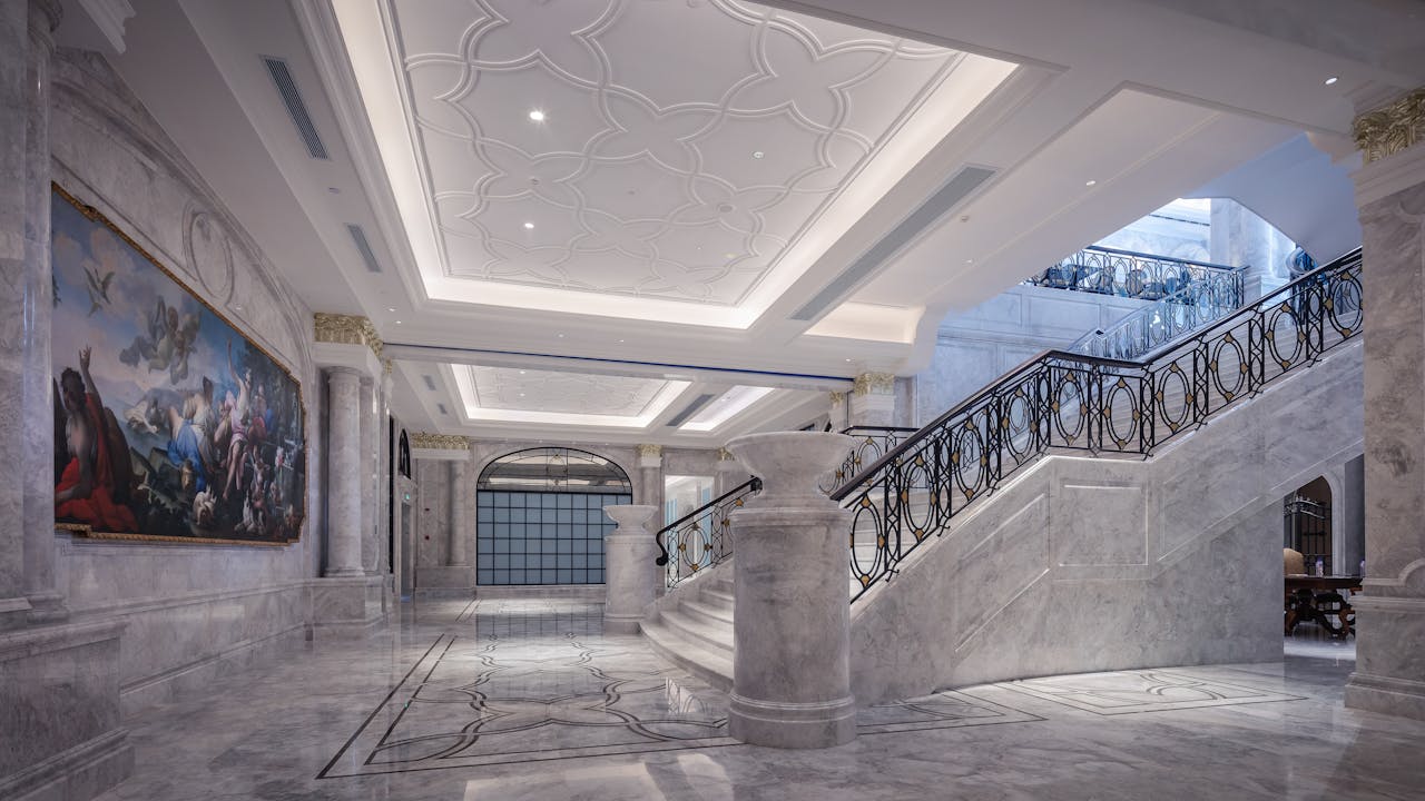 Elegant marble hallway featuring a grand staircase and ornate ceiling design.