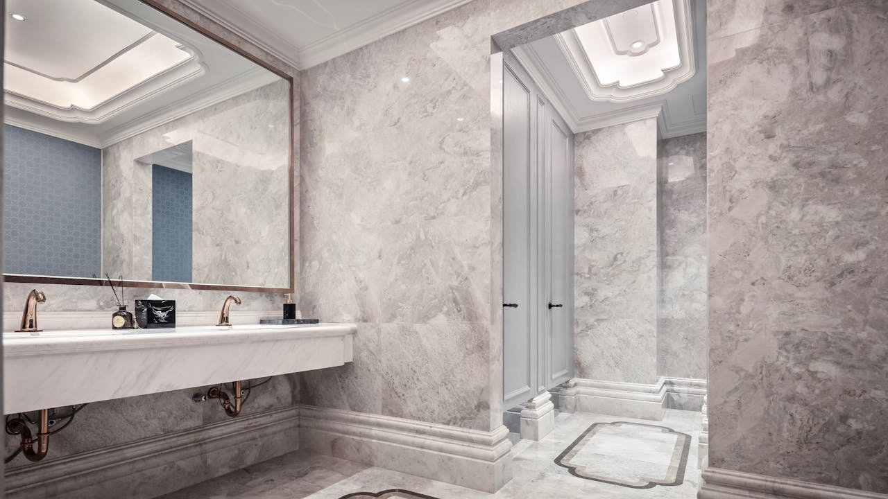 Luxurious bathroom interior with marble walls, large mirror, and modern fixtures, showcasing elegant design.