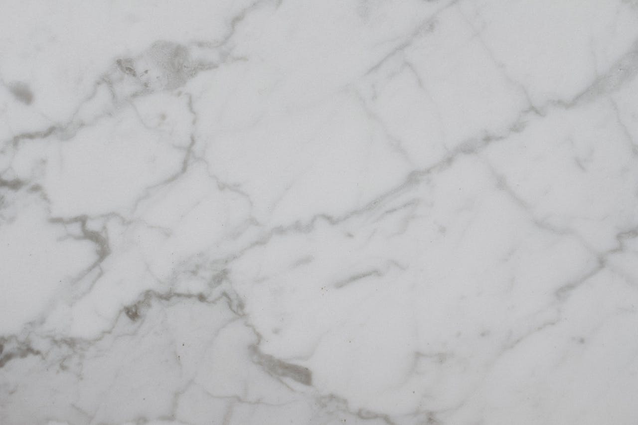 Close-up of a smooth white marble surface with natural veining, ideal for backgrounds.