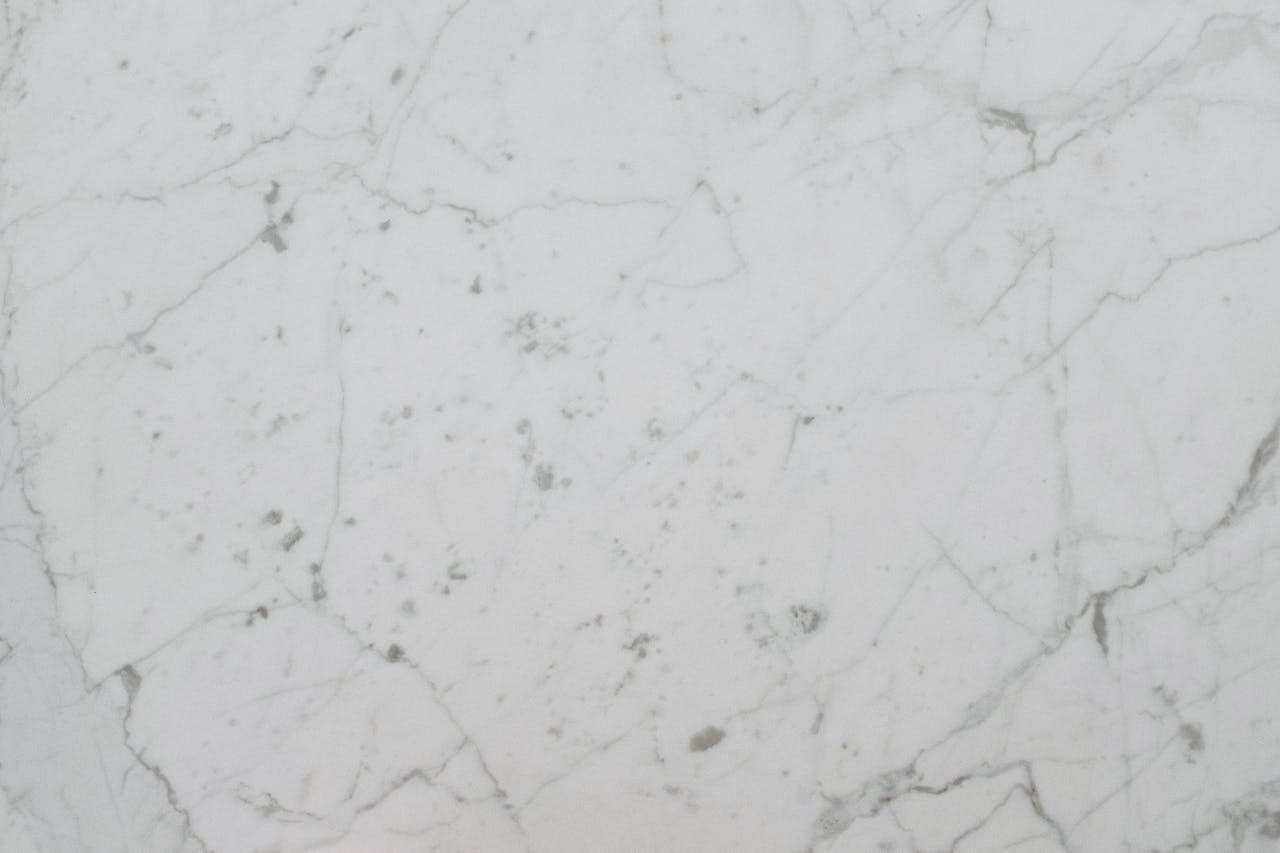 High-resolution image of a white marble surface with natural veining, ideal for backgrounds and design use.